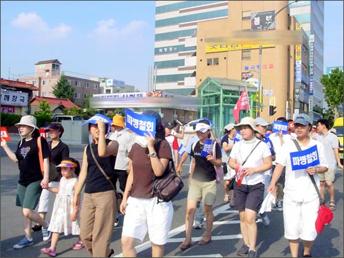 여성, 어린아이 참가자들이 내리쬐는 땡볕에 불편해 하고 있다. 